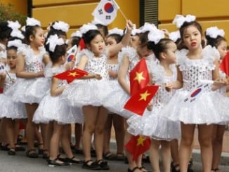 School girls hold Vietnamese and South Korean flags while waiting for arrival of South Korean President Moon Jae-in before a welcoming ceremony at the Presidential Palace in Hanoi, Vietnam (March 23, 2018). Image Credit: Kham/Pool Photo via AP